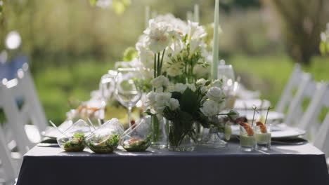 Wunderschönes-Blumendekor-Und-Köstliche-Vorspeisen-Auf-Dem-Tisch-Im-Blühenden-Garten-Im-Frühling,-Nahaufnahme